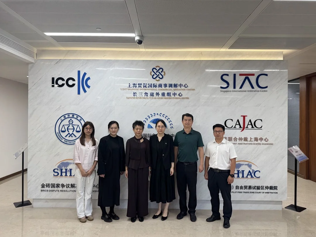 六位调研人员站在多个国际商事调解与仲裁机构标识墙前的合影